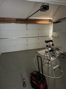 Garage door repair technician inspecting opener and cable system after a snapped garage door cable in Long Beach CA